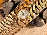 a gold bracelet with a watch on top of it