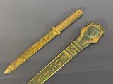 deux objets dorés et verts exposés dans une vitrine