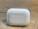 Des AirPods de la marque Apple sont posés sur une table en bois, dans un étui transparent