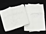 deux serviettes blanches ornées de motifs brodés sur fond noir
