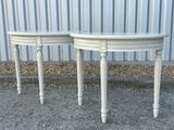 une paire de tables d'appoint peintes en blanc, posées sur un sol recouvert de gravier devant un bâtiment