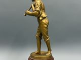 figurine en bronze représentant un garçon tenant une batte de baseball, posée sur un socle en bois