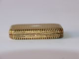 a close up of a gold cigarette case on a white surface