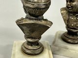 two statues of a man and a woman on marble bases