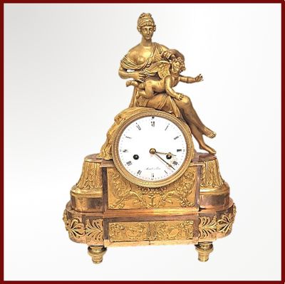 une horloge en or avec une femme assise dessus