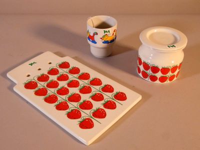 une assiette blanche ornée d'un motif de fraise, posée à côté d'une tasse et d'une soucoupe