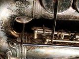 a close up of an old silver saxophone on the ground