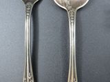 two silver spoons and a fork on a table
