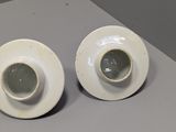 two white plates on a table with a cup and saucer on it