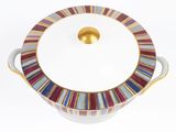 a white bowl with a gold lid and colorful stripes on it