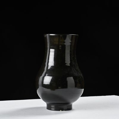 a black vase that is sitting on a white table