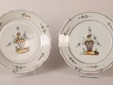 two plates with flowers on them are sitting on a stand