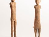 two figurines of a man and a woman standing on a wooden base