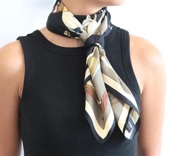 a woman wearing a black tank top with a scarf around her neck