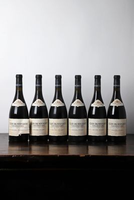 six bottles of wine sit on a table in front of a wall