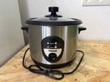 a silver and black crock pot on a wooden table