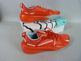 a pair of orange sneakers with a box on a white surface