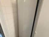 un grand réfrigérateur blanc dans un coin de la salle de bains