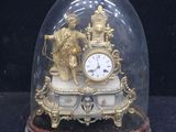 a gold clock under a glass dome on a black surface