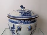a blue and white bowl with a lid on a glass table