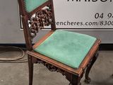 pair of antique chairs with green upholstered cushions in front of a sign