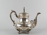 a silver teapot with a handle and a handle on a stand