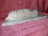 a stone sculpture of a sheep on a red cloth