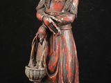 une vieille statue représentant une femme avec un panier sur l'épaule