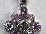 un gros plan d'un pendentif violet et bleu sur une surface blanche