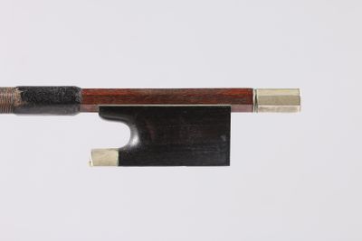 un gros plan d'un archet de violon posé sur une surface blanche