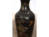 a black vase with gold designs on it sitting on a table