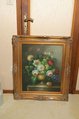 une photo d'un tableau posé par terre à côté d'un vase de fleurs