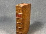 an old book is sitting on a table with a gray background