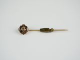 a close up of a metal pin with a flower on it