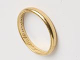 gros plan d'une bague en or sur une surface blanche