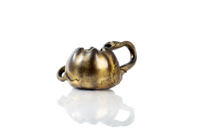 a gold teapot with a handle on a white surface