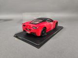 red ferrari sports car in a clear display case on a gray surface