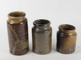 three brown and black vases sitting next to each other on a white surface
