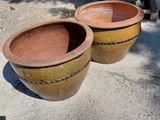 two large brown pots sitting on the ground