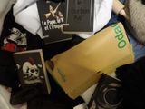 a pile of clothing and books sitting on a bed