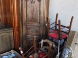 de nombreuses caisses et chaises dans une pièce où se trouve une armoire en bois