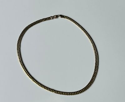 gros plan d'un collier à chaîne en or sur une surface blanche