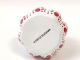 a white bowl with red dots on it sitting on a white surface