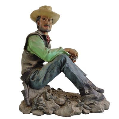 statue d'un homme assis sur un rocher, coiffé d'un chapeau de cow-boy