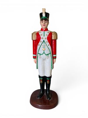 petit soldat en bois vêtu d'un uniforme rouge et vert, sur fond blanc