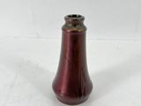 un vase rouge posé sur une surface blanche