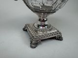 a silver bowl with a handle on a stand