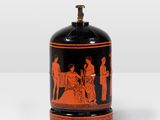 an orange and black vase sitting on top of a white table