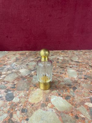 gold and glass perfume bottle on a marble table with red background