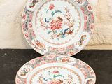two plates with floral designs on them sitting on a table
